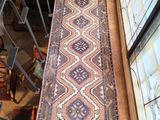 une photo montrant un long tapis posé sur un parquet, près d'une fenêtre