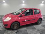 La petite voiture rouge est garée dans le garage, sur le sol à damier.