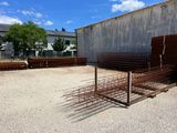 a large pile of rusted steel bars in front of a building