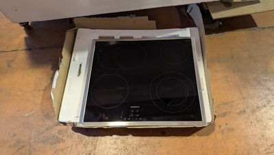 une boîte posée par terre, contenant une plaque de cuisson à l'intérieur