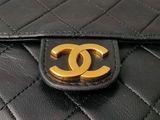 a close up of a black purse with a gold logo on it