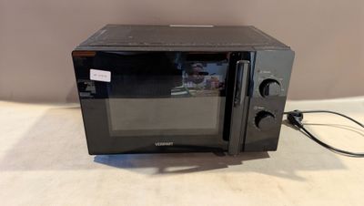 un micro-ondes noir posé sur une table, avec un cordon d'alimentation qui y est branché