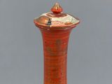 a red vase with a lid sitting on a table