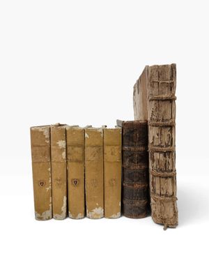 plusieurs vieux livres sont empilés sur une surface blanche