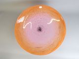 un saladier en verre orange percé d'un trou noir