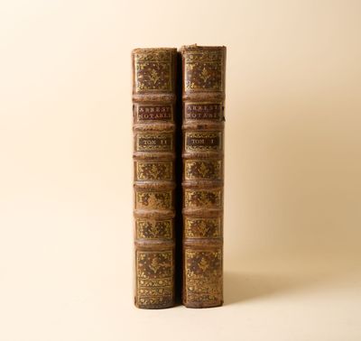 deux vieux livres posés l'un sur l'autre sur une surface blanche