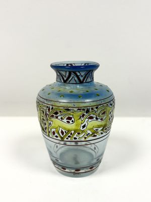 un vase bleu et vert posé sur une surface blanche