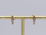 a pair of gold and diamond earrings on a stand