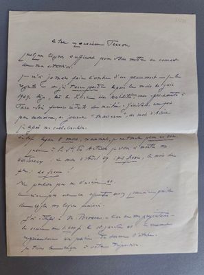 une vieille lettre manuscrite, posée sur un morceau de papier, sur une table