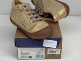 gold leather sneakers with laces on top of a cardboard box