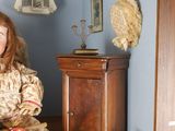 a doll sitting on a shelf in the corner of a room