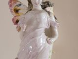 a figurine of a woman with a butterfly on her shoulder