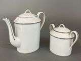 two white porcelain teapots and a saucer on a table