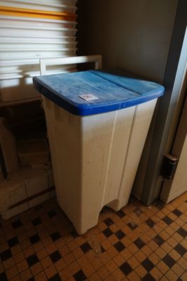 une poubelle posée dans un coin de la pièce, près d'une fenêtre