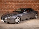 a silver sports car parked in front of a brick wall
