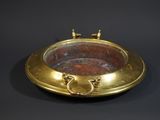 an image of a brass bowl with handles on a black background
