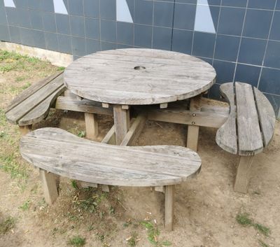 a wooden table and two benches in front of a blue wall