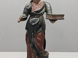 statue d'une femme tenant un plateau de nourriture posé sur une surface blanche