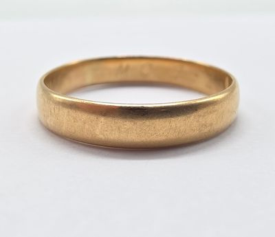 a close up of a gold wedding ring on a white surface