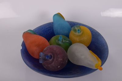 un saladier bleu rempli de fruits et de légumes posé sur une table blanche