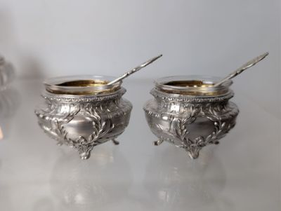 two silver bowls with spoons on a table
