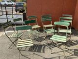 six green chairs sitting in a circle on the sidewalk