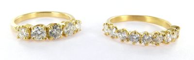 two gold rings with diamonds on them on a white surface