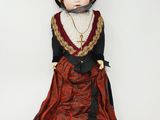 un gros plan d'une poupée portant une robe rouge et un chapeau noir