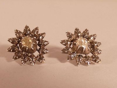 a pair of silvertone earrings on a white surface