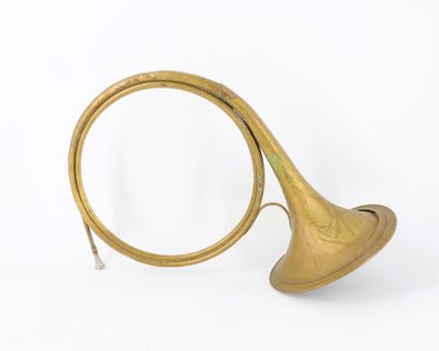 an antique brass french horn with a brass bell on a white background