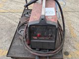 a welding machine sitting on a cart in a parking lot