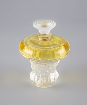 flacon de parfum en verre jaune, muni d'un bouchon doré et orné d'une fleur sur le dessus
