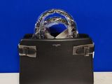 un sac à main noir muni d'une poignée argentée, posé sur une table blanche