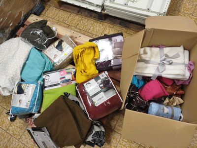 un carton rempli de vêtements et d'autres objets posé par terre