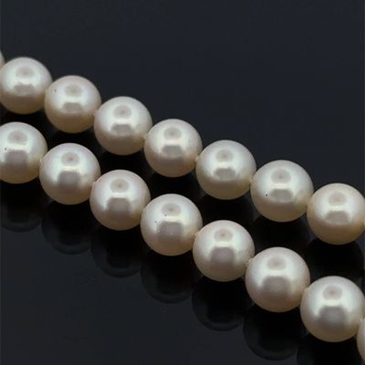 a close up of a strand of white pearls on a black surface