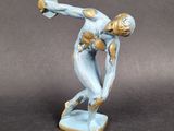 statue of a man holding a tennis racquet on top of a table