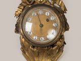 une horloge en or sur le mur avec un oiseau dessus