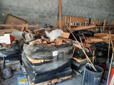 un gros tas de bois dans un entrepôt où se trouvent de nombreux autres objets