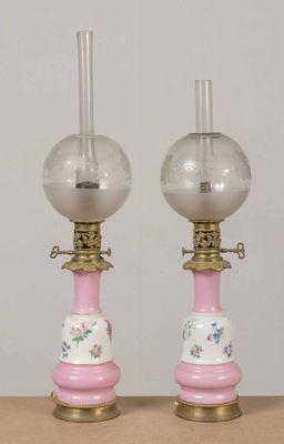 une paire de lampes en verre rose ornées de finitions dorées, posées sur une table en bois