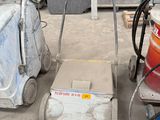 a machine that is sitting on the ground next to a bucket