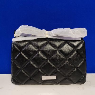 black quilted purse with a white bow on top of it