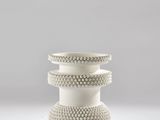 trois vases blancs empilés les uns sur les autres sur une surface blanche