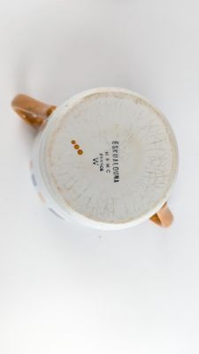 une tasse blanche avec une anse marron posée sur une surface blanche