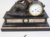 a statue of a woman with a clock on top of a table