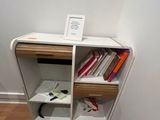 a small book shelf with books on it next to a chair