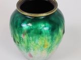 a green vase with a gold rim sitting on a white surface