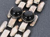 an image of a close up of a silver bracelet with black beads