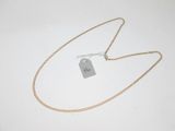 une chaîne en or à laquelle est accrochée une médaille, posée sur une surface blanche
