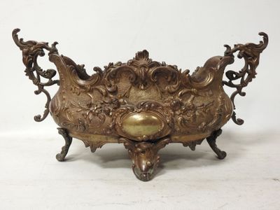 Plaque en laiton ancien avec un motif ouvragé, posée sur un socle, sur fond blanc