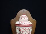 a red and white vase sitting on a wooden chair